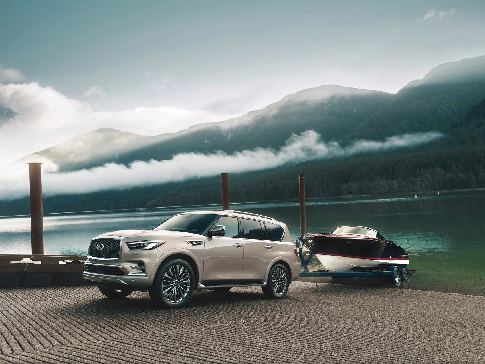 Infiniti QX80 backing a boat into a lake